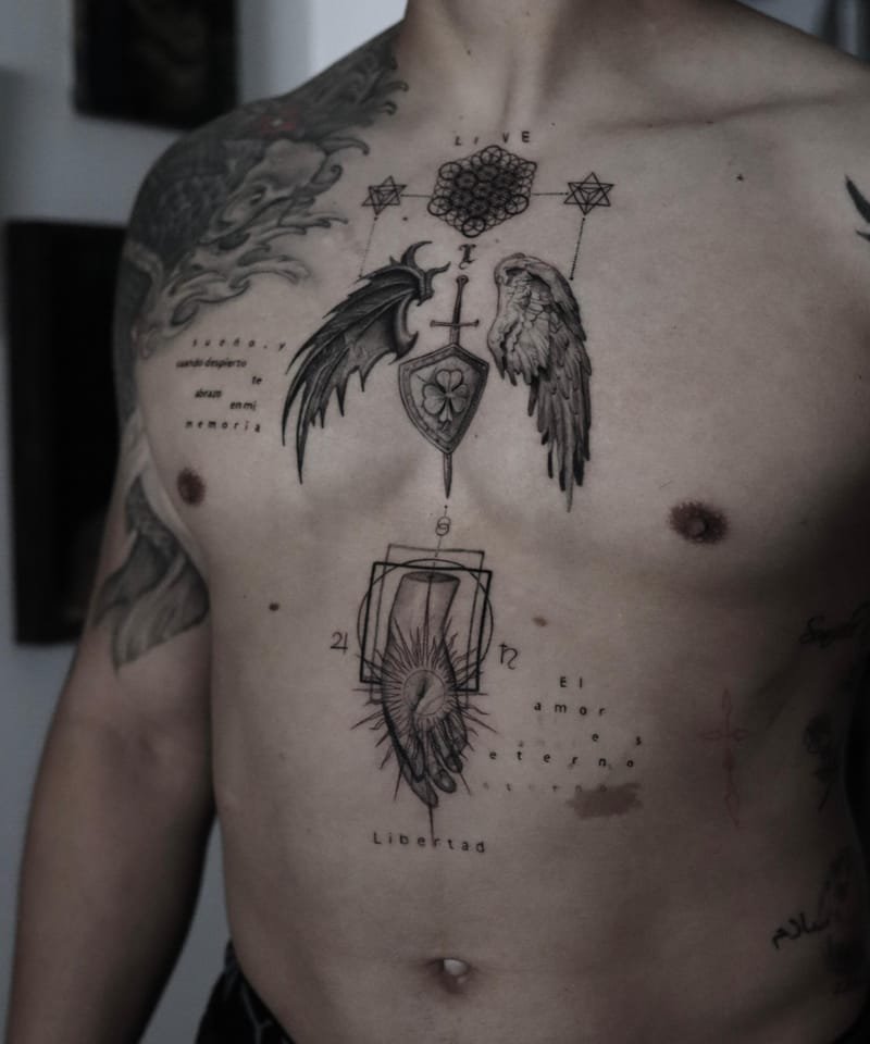 Plano más abierto del torso: bajo el escudo aparece una mano que sostiene un ojo radiante dentro de dos rectángulos, con las palabras Libertad y El amor es eterno tatuadas en letras pequeñas.