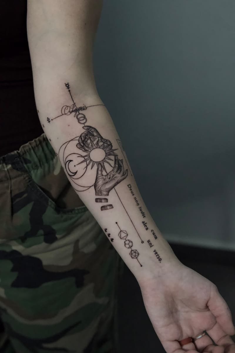 El antebrazo con la mano abierta: la composición entera, del símbolo alquímico de arriba a la frase latina junto a la muñeca.